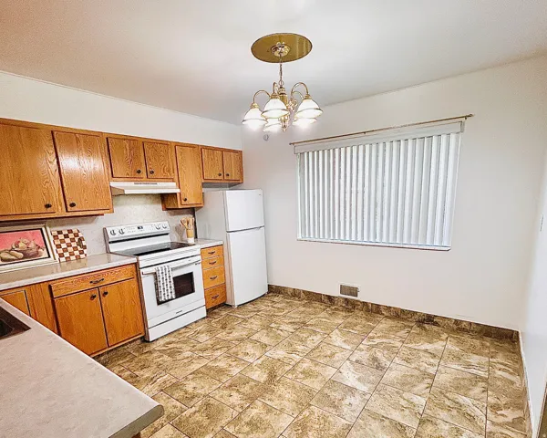 Kitchen featuring wood cabinetry, laminate countertops, a white range, a white refrigerator, and tiled flooring
