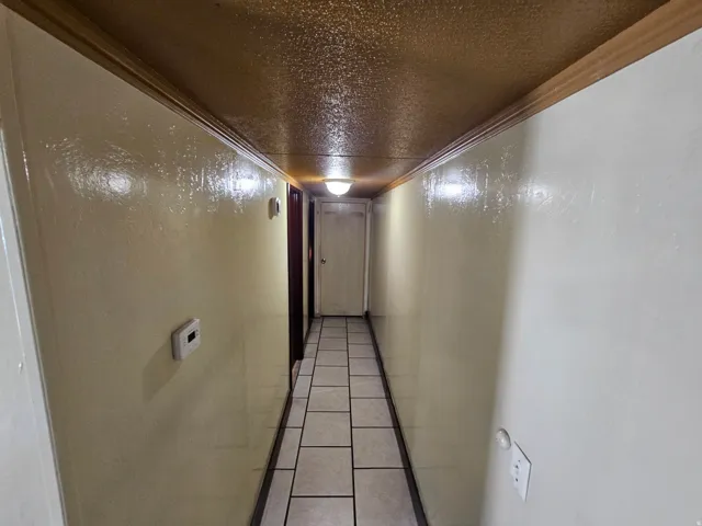 Hall featuring tile patterned floors, a textured ceiling, and ornamental molding
