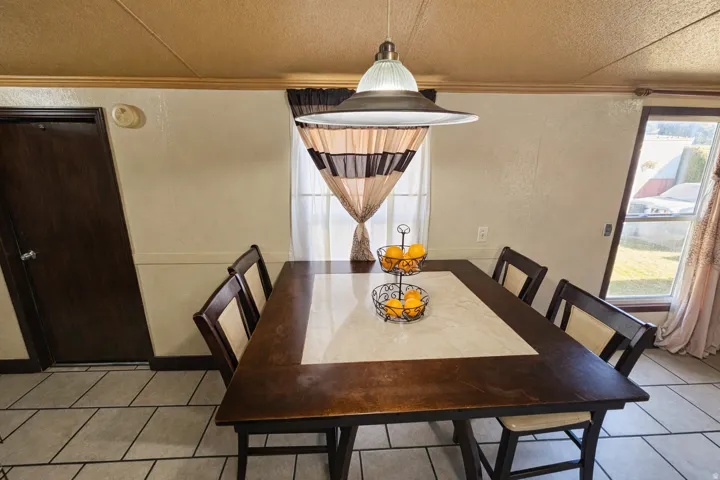 Dining room with crown molding, light tile patterned flooring, and a textured ceiling