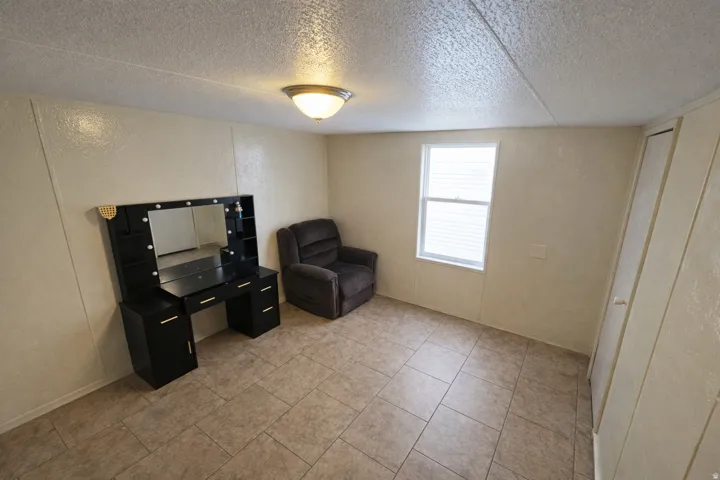 Sitting room with a textured wall, a textured ceiling, and light tile patterned floors