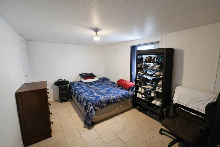 Bedroom with a textured ceiling, a decorative wall, and light tile patterned floors