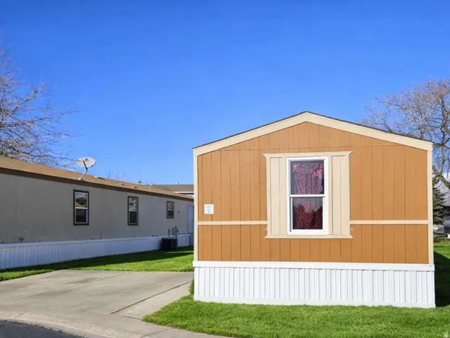 View of home's exterior with a lawn and a storage unit