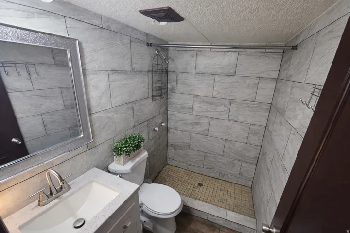 Bathroom featuring vanity, a stall shower, tile walls, and a textured ceiling