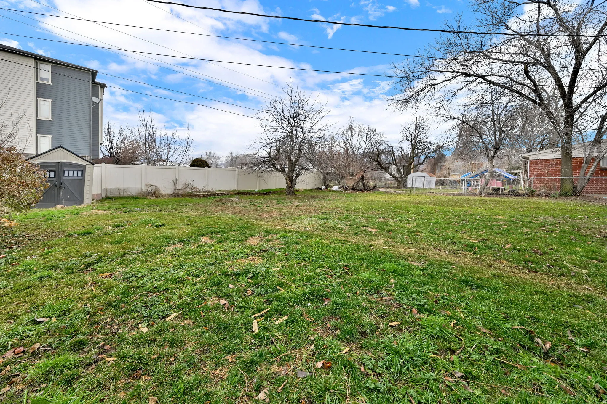 Fenced backyard featuring a shed