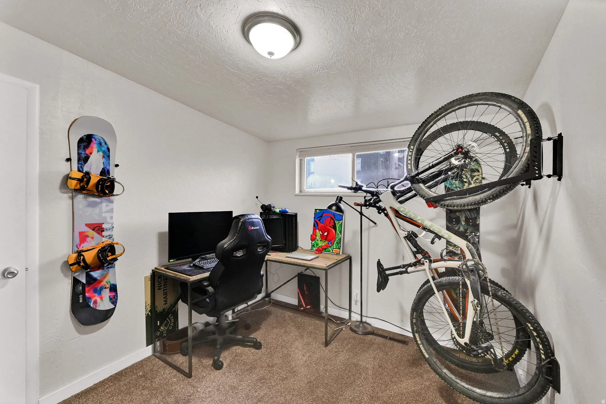 Carpeted home office with a textured ceiling and baseboards