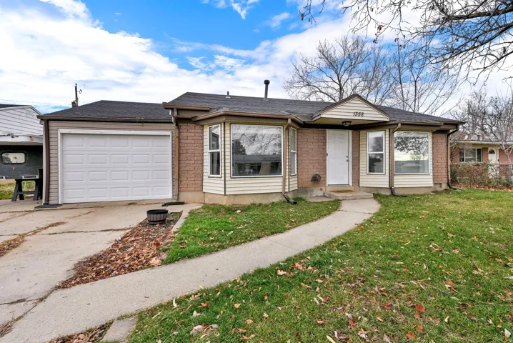 Single story home featuring a front yard, a garage, brick siding, and driveway