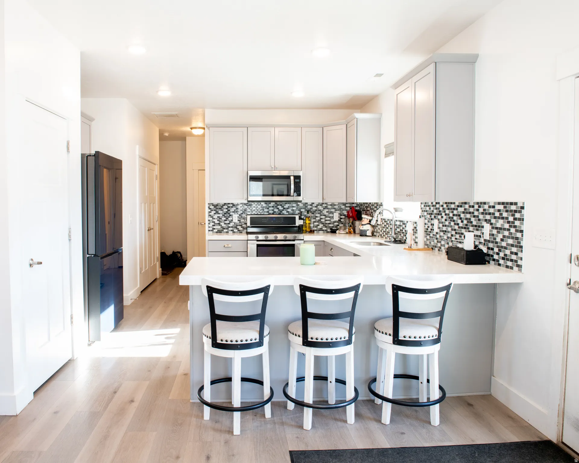 Kitchen with stainless steel appliances, a peninsula, a kitchen breakfast bar, tasteful backsplash, and recessed lighting