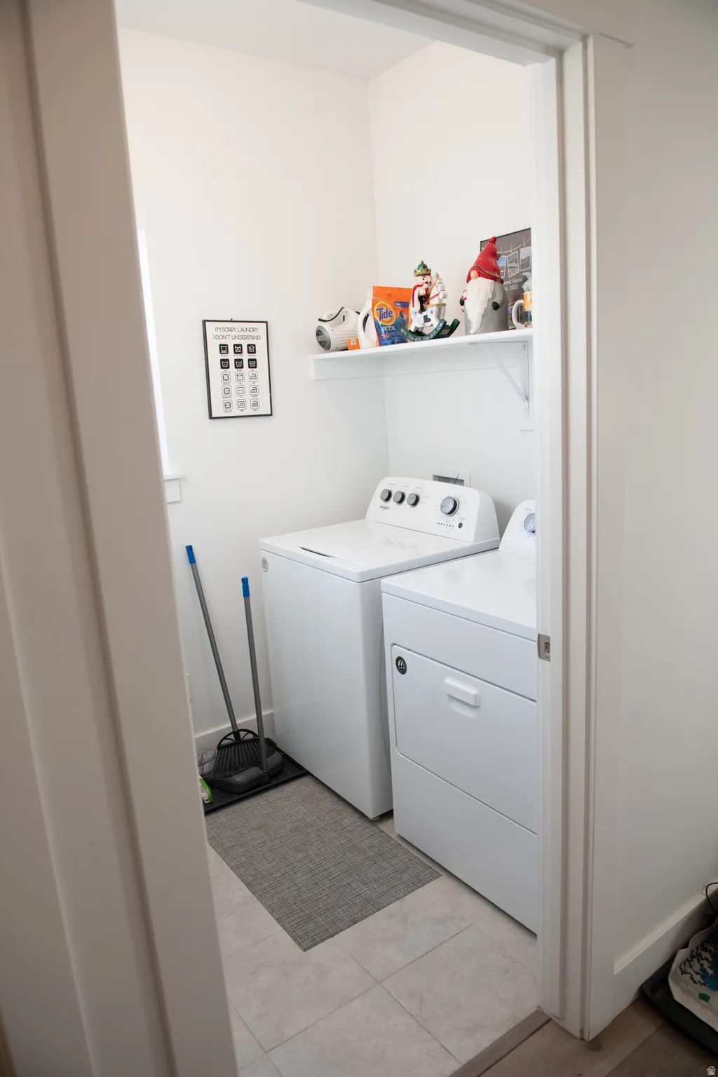 Laundry area with washer and clothes dryer and light tile patterned floors