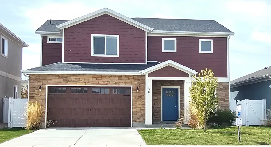 View of front of property featuring stone siding, a gate, an attached garage, and driveway