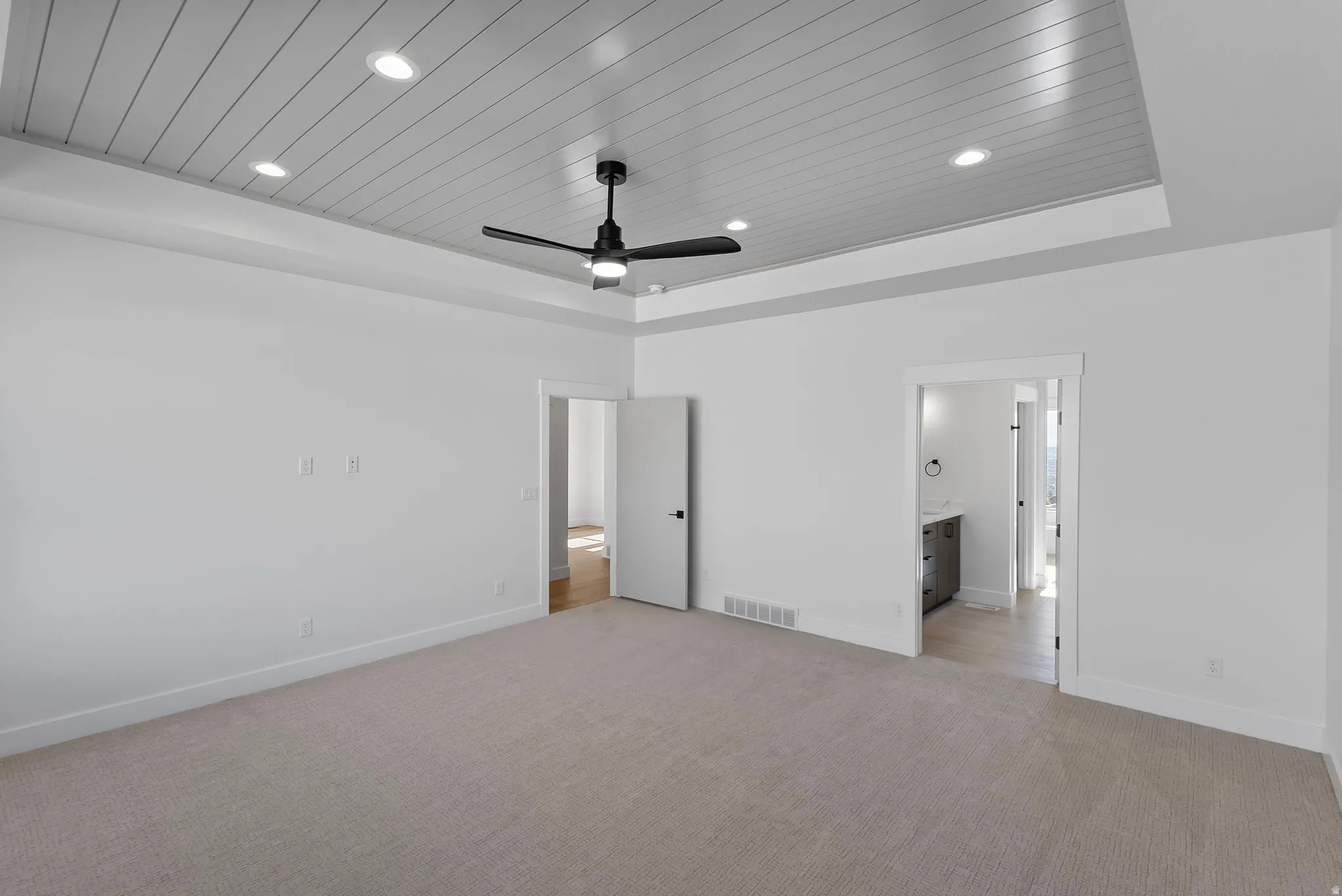 Unfurnished bedroom with wooden ceiling, light colored carpet, a ceiling fan, a raised ceiling, and recessed lighting