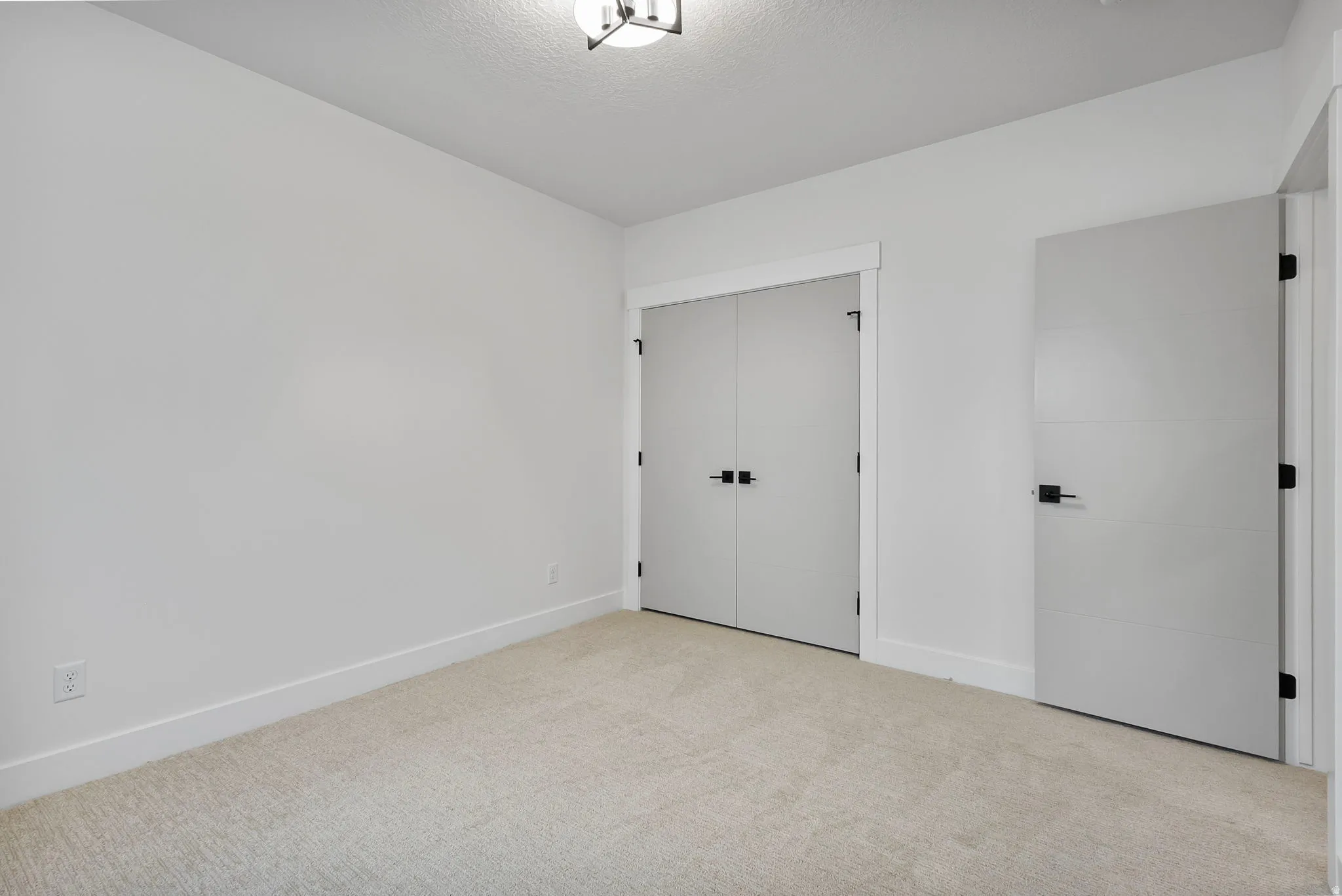 Room featuring light neutral-toned carpeting, white walls, and a modern ceiling light fixture