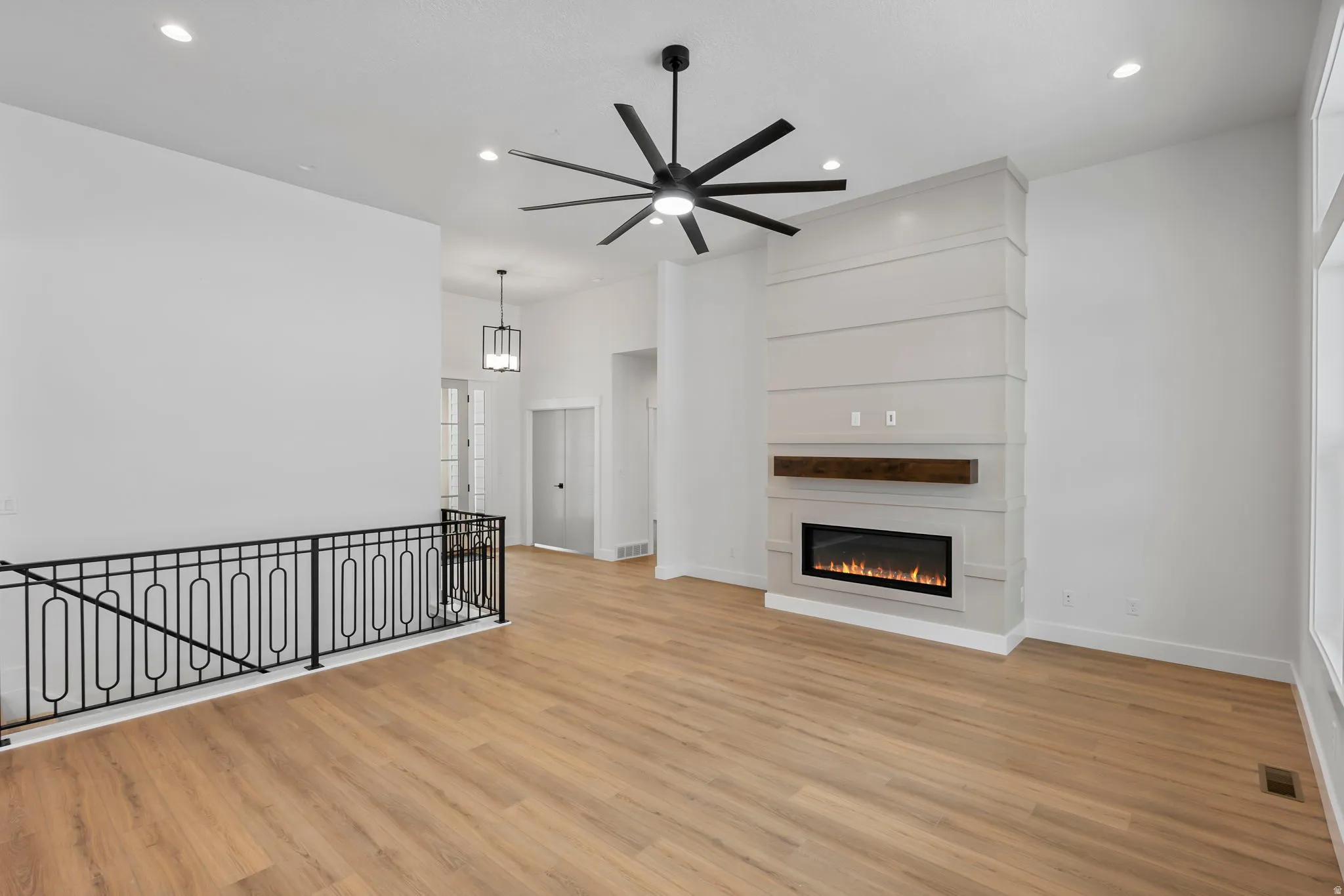 Unfurnished living room featuring a glass covered fireplace, a ceiling fan, light wood-style flooring, and recessed lighting