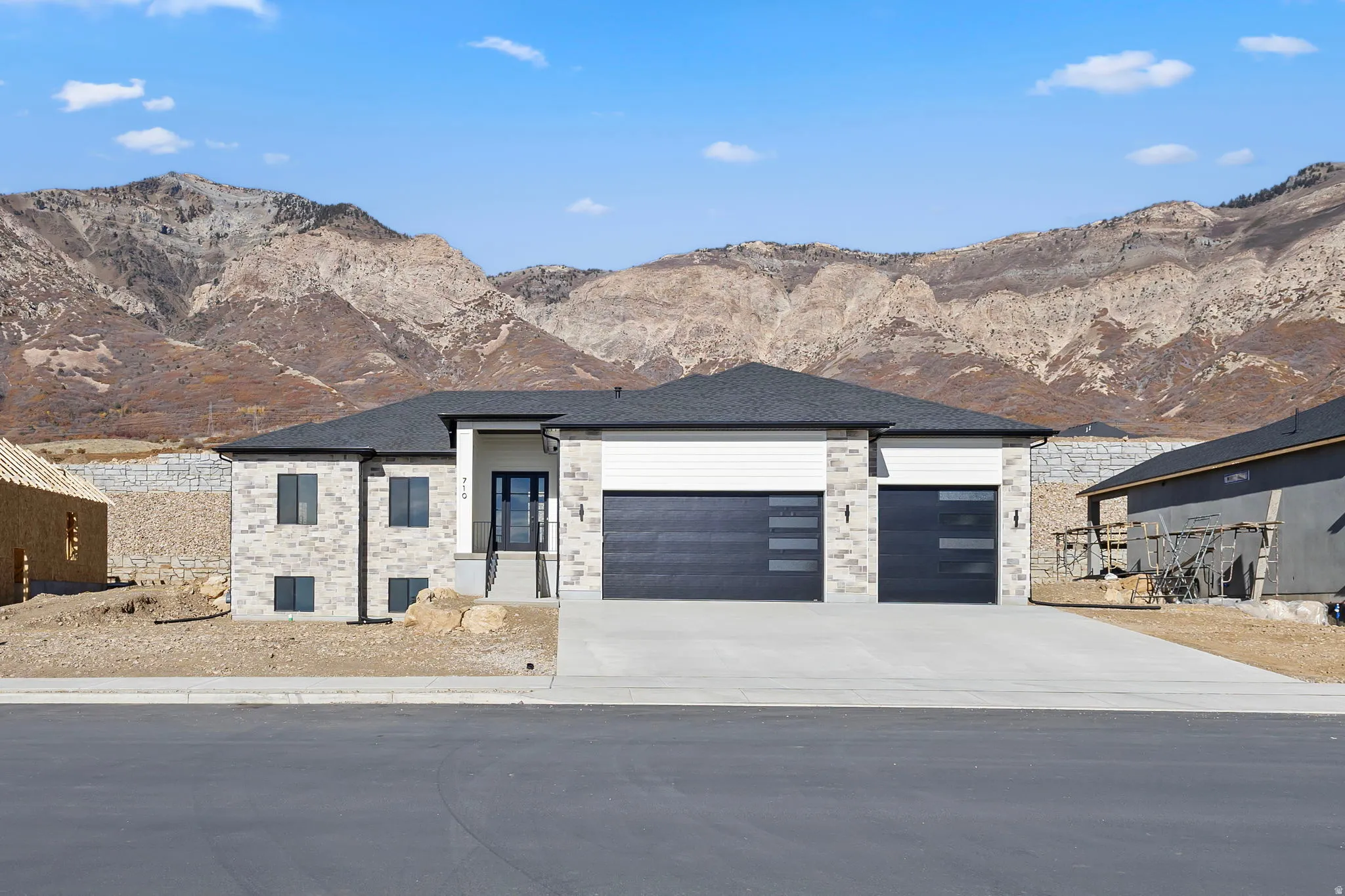 View of front of property with a mountain view, concrete driveway, a garage, and a shingled roof
