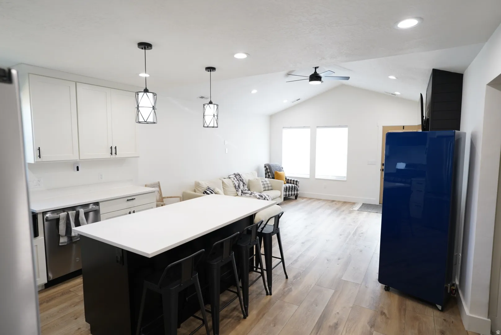 Kitchen featuring dark cabinetry, a breakfast bar, white cabinetry, pendant lighting, and dishwasher