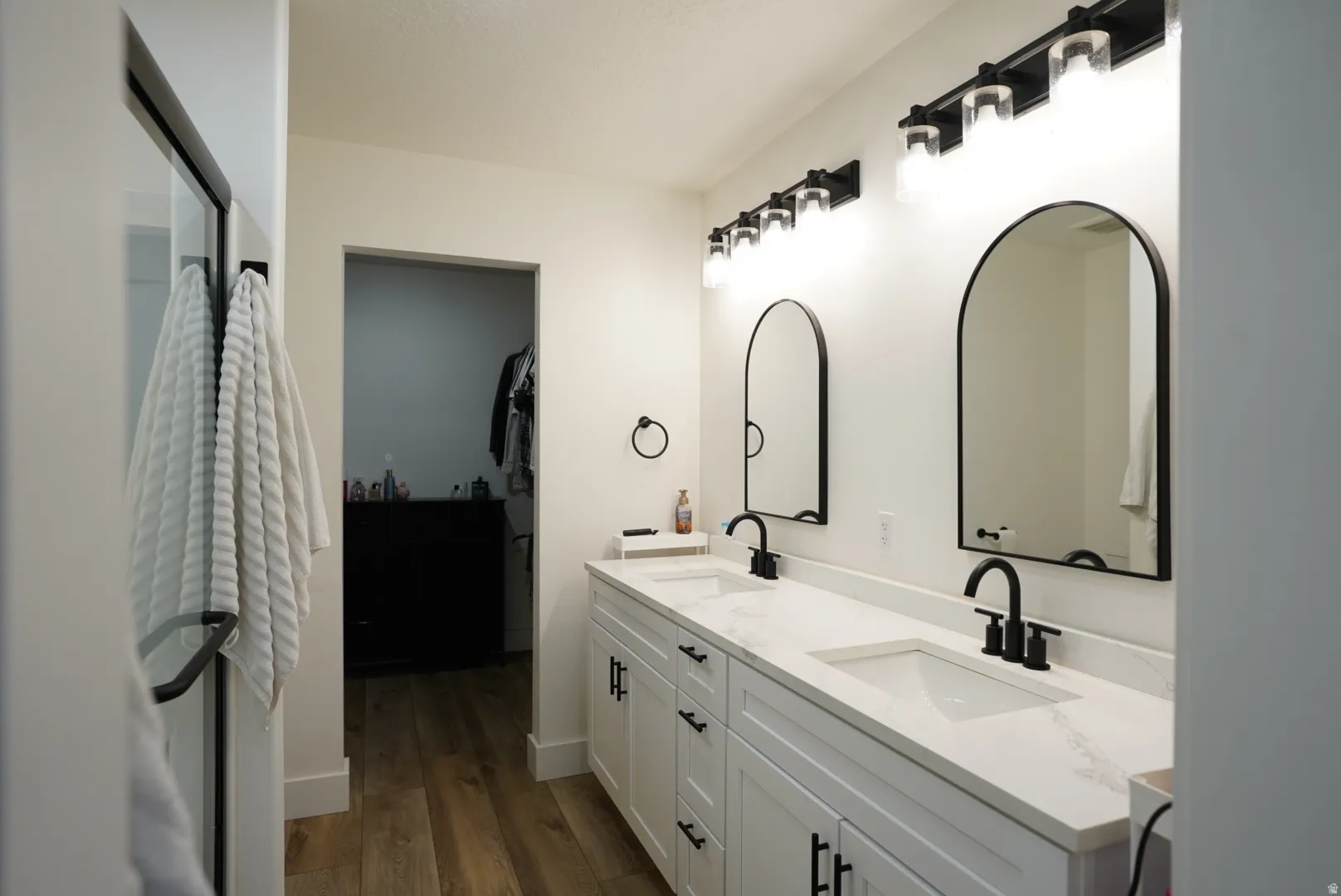 Full bathroom featuring double vanity, dark wood finished floors, and a walk in closet