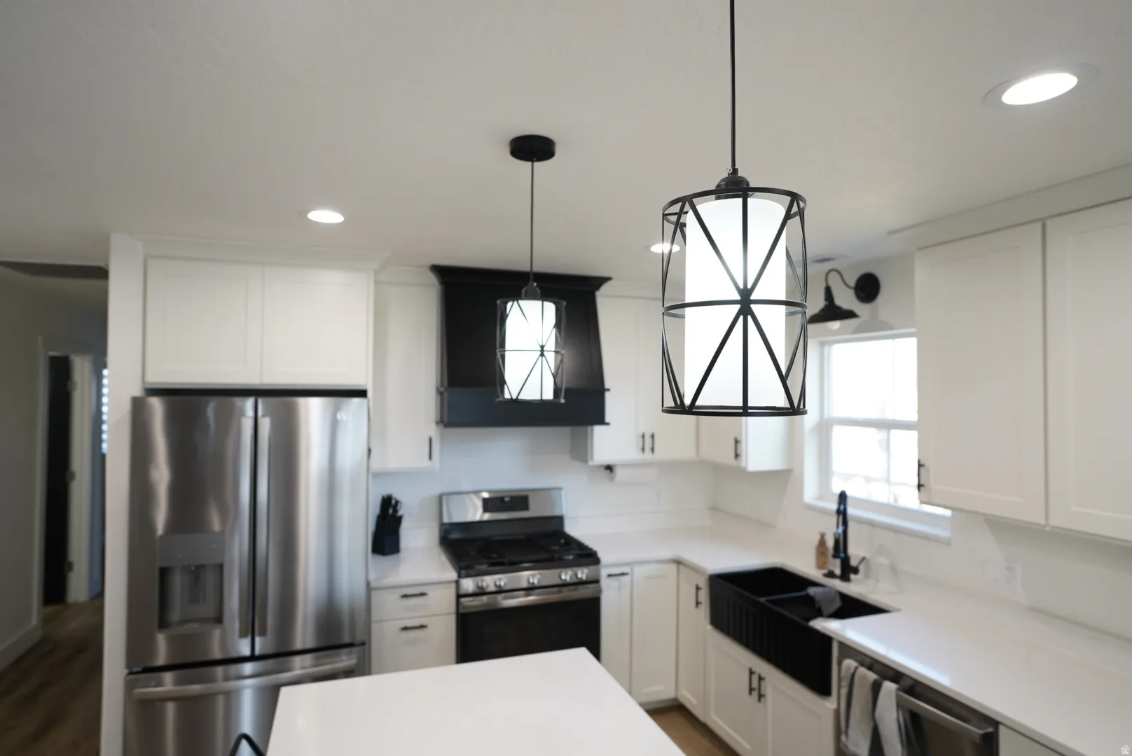 Kitchen with stainless steel appliances, white cabinetry, hanging light fixtures, recessed lighting, and dark wood finished floors