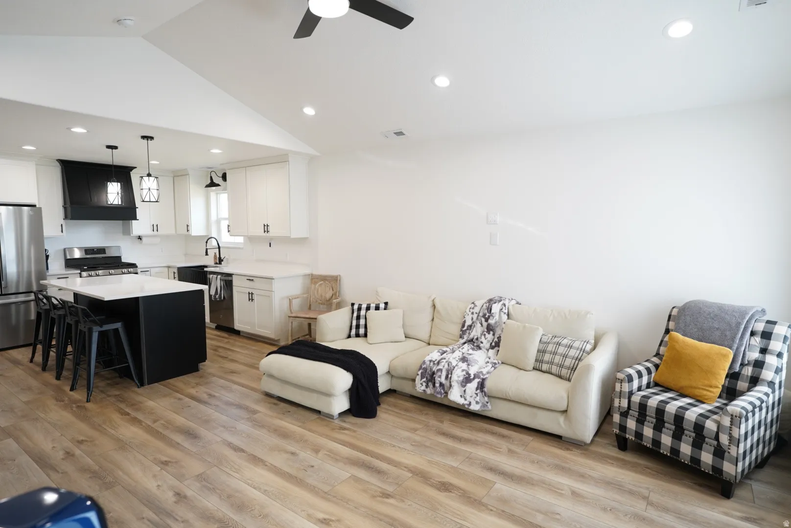 Living area with light wood-type flooring, vaulted ceiling, a ceiling fan, and recessed lighting