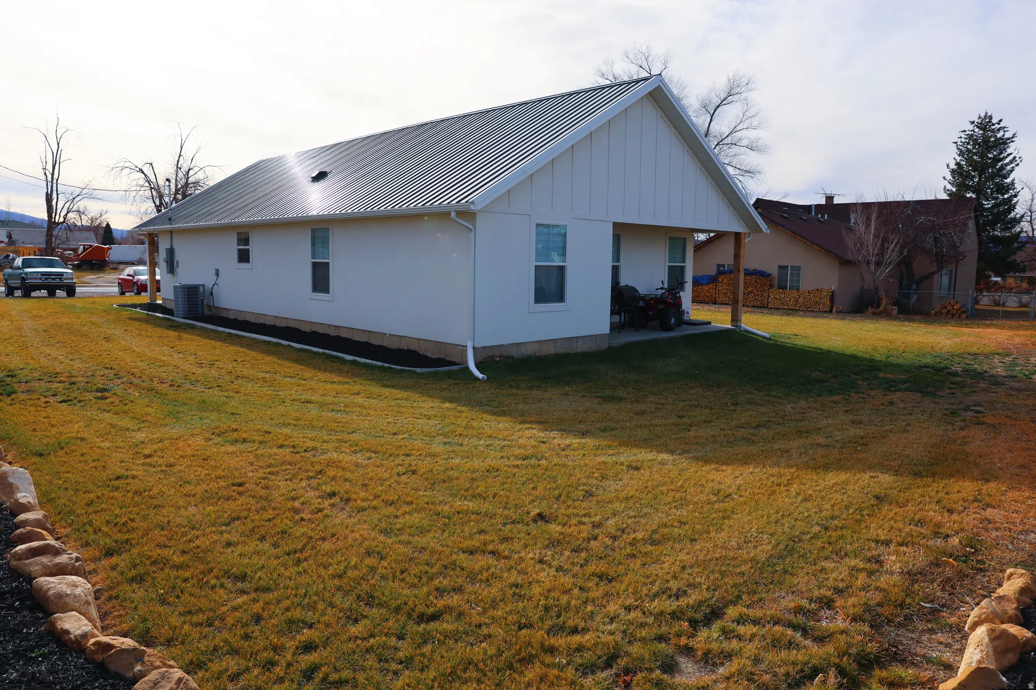 Rear view of house featuring a metal roof, a standing seam roof, a lawn, and a patio