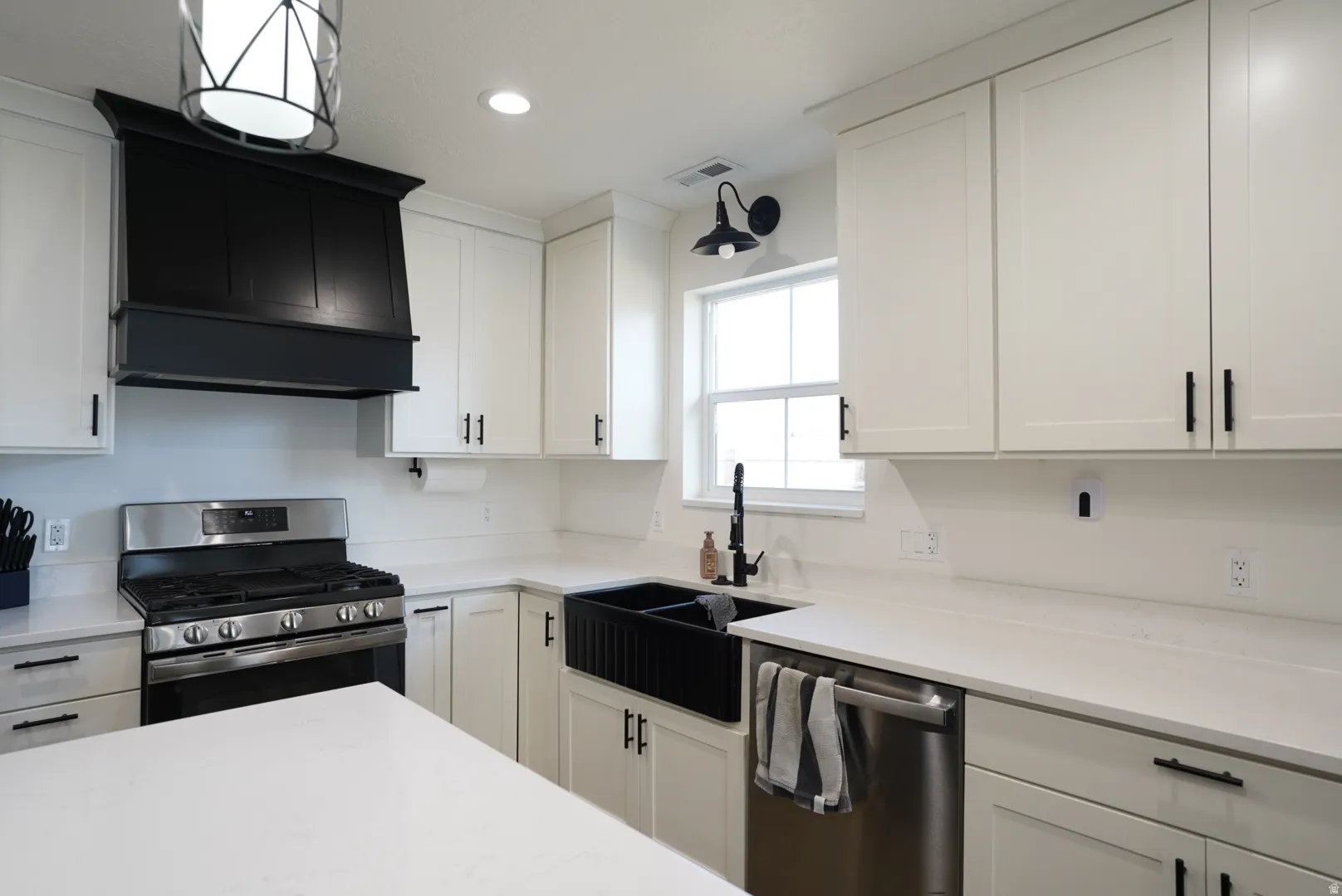 Kitchen with appliances with stainless steel finishes, white cabinets, wall chimney exhaust hood, recessed lighting, and light stone counters