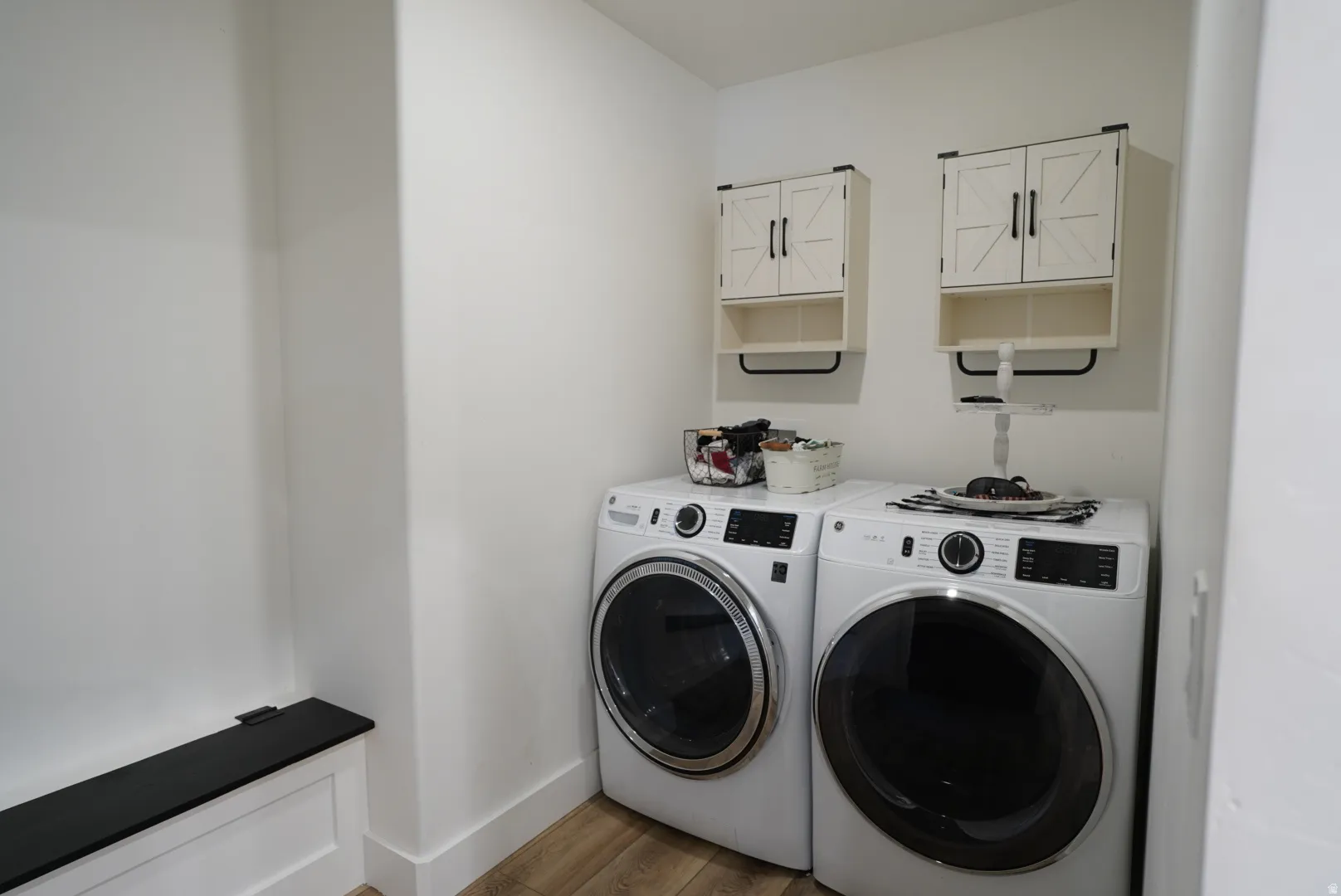 Washroom featuring cabinet space, washing machine and clothes dryer, and light wood-style flooring
