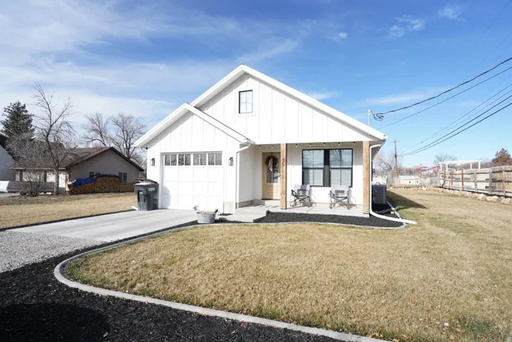 Modern farmhouse style home featuring covered porch, concrete driveway, and a front lawn