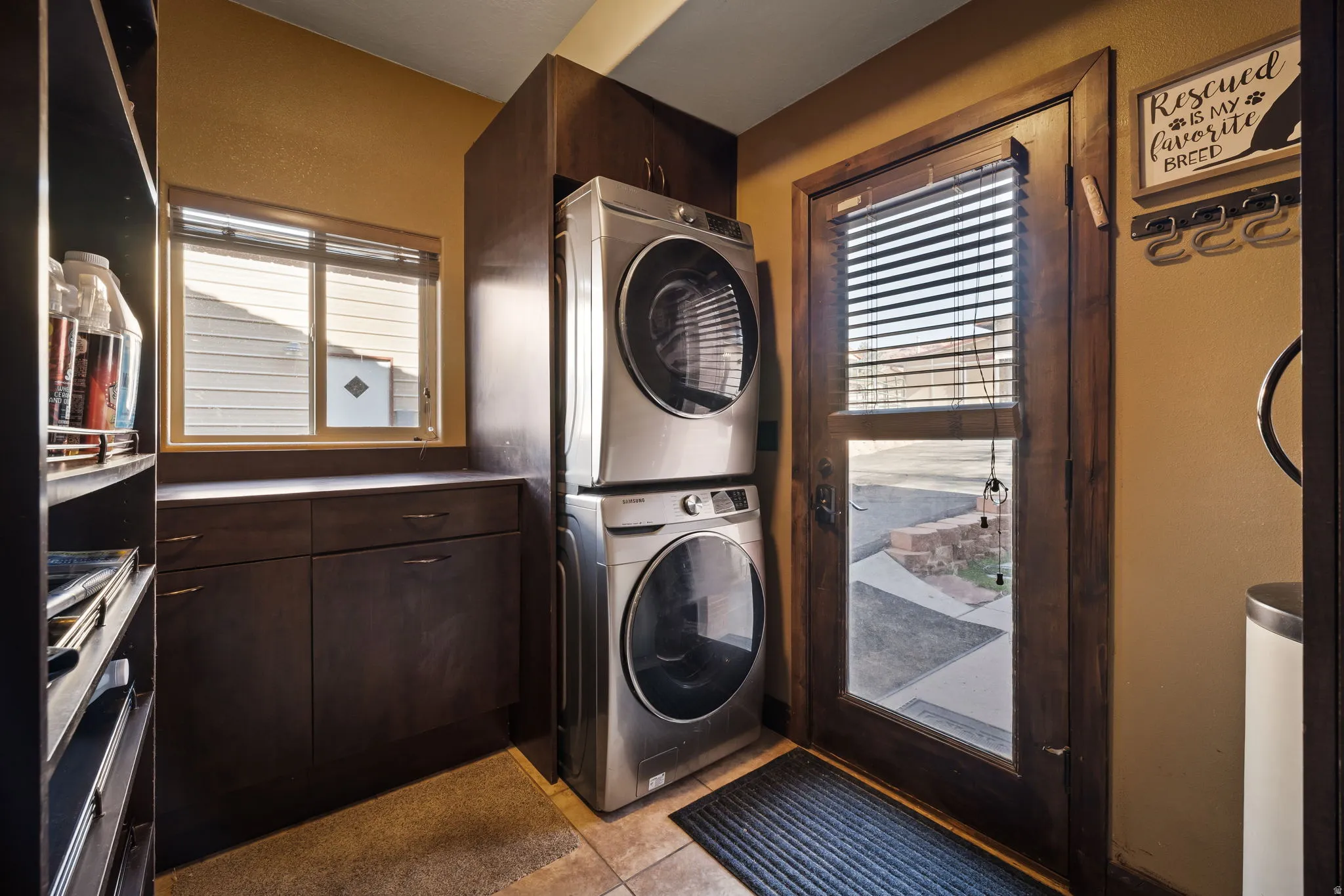 Laundry area featuring stacked washer / drying machine and light tile patterned flooring