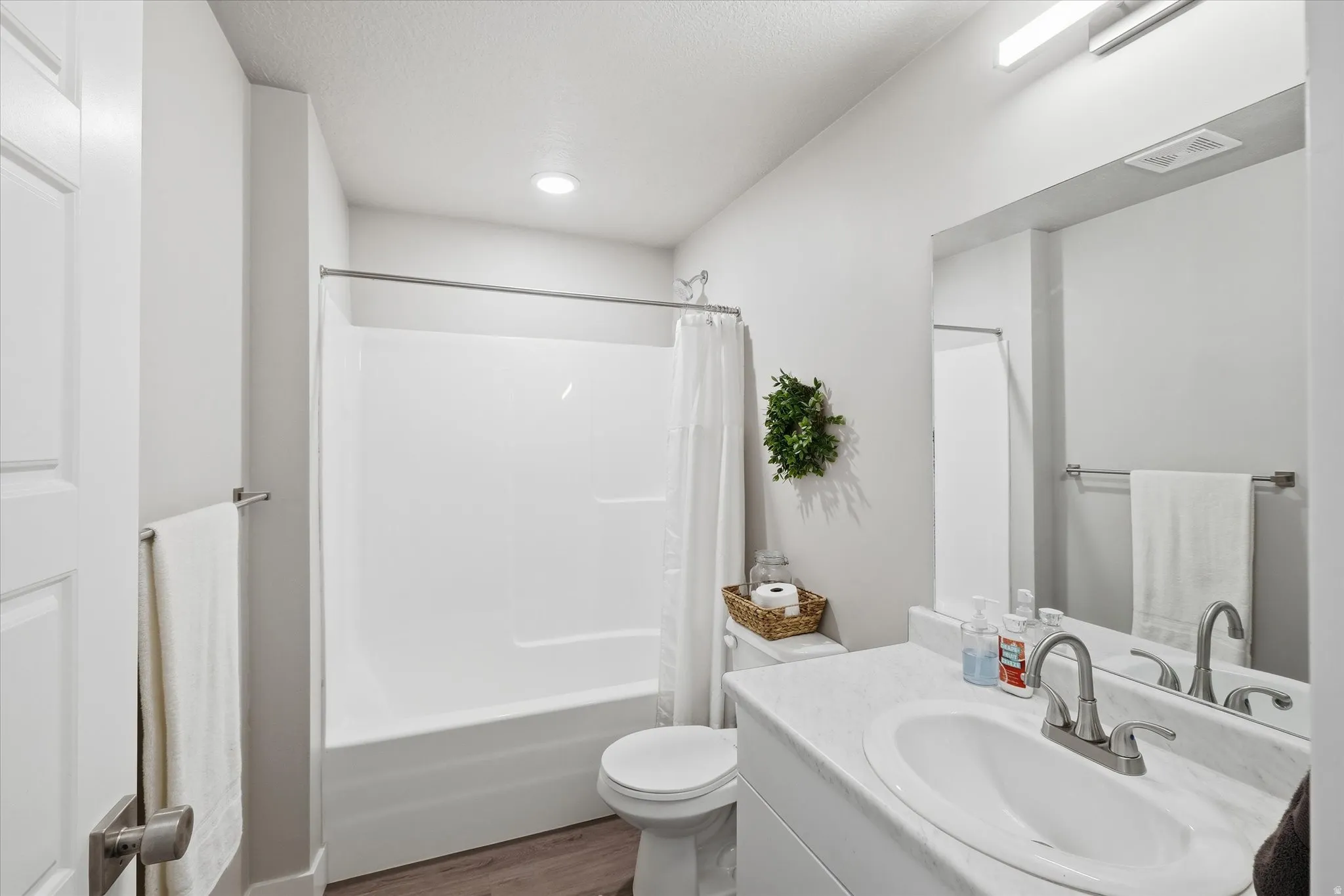 Bathroom featuring vanity, shower / tub combo, and dark wood finished floors