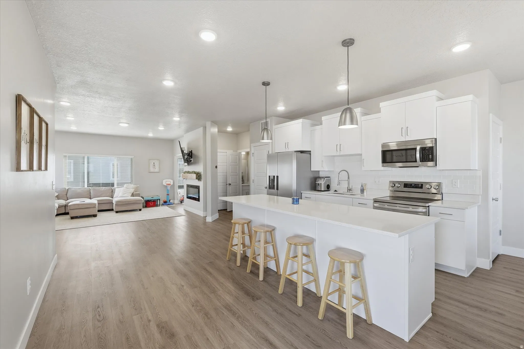 Kitchen featuring white cabinetry, appliances with stainless steel finishes, a breakfast bar area, open floor plan, and recessed lighting