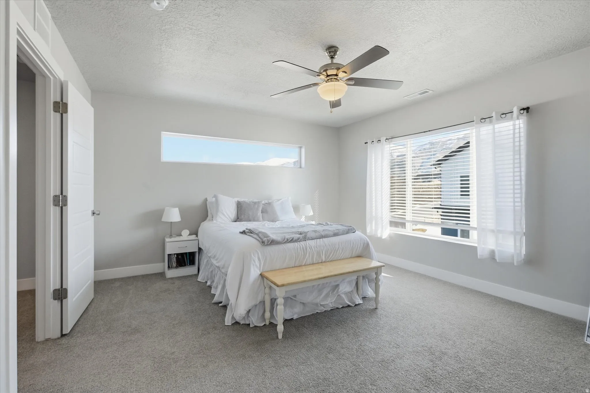 Bedroom with a textured ceiling, light carpet, and ceiling fan