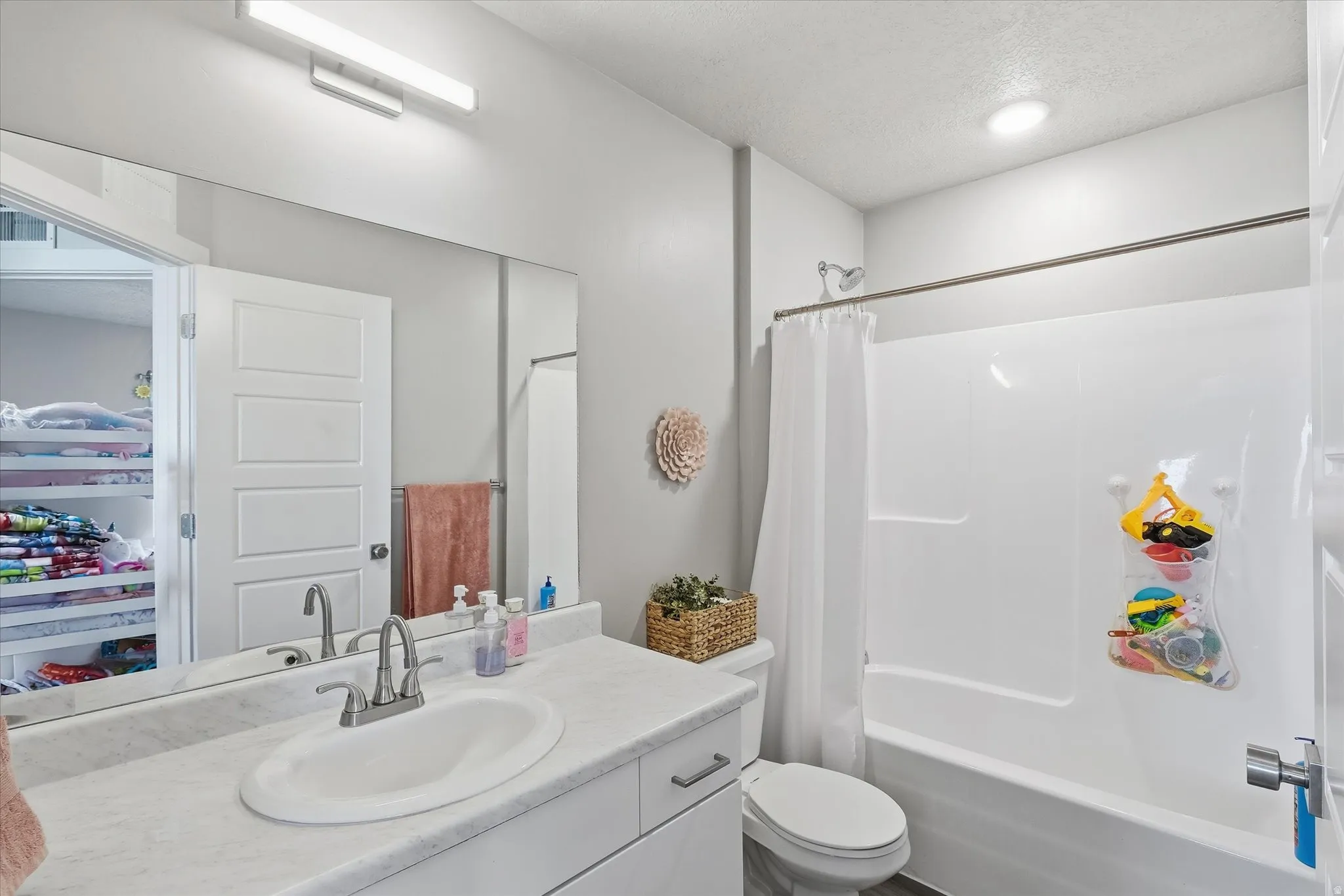 Bathroom featuring shower / bathtub combination with curtain, vanity, and a textured ceiling