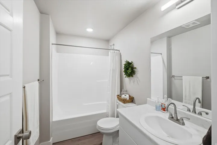 Bathroom featuring vanity, shower / tub combo, and dark wood finished floors