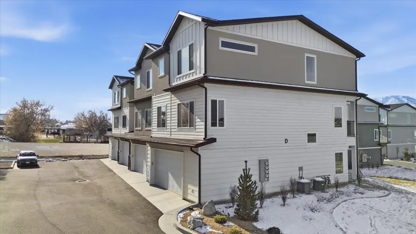 View of side of home featuring a residential view, a garage, asphalt driveway, and board and batten siding