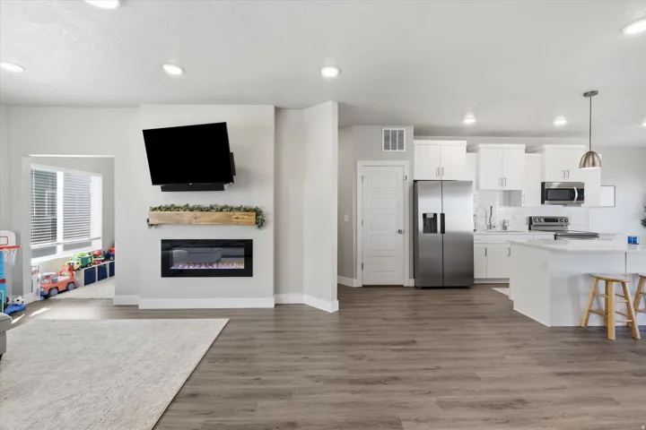 Kitchen with open floor plan, white cabinets, appliances with stainless steel finishes, decorative light fixtures, and a breakfast bar