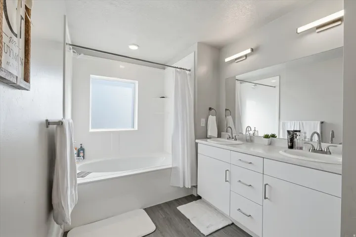 Bathroom with shower / tub combo with curtain, double vanity, a textured ceiling, and dark wood-style flooring