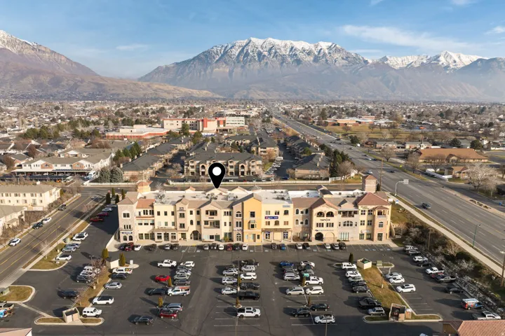 Aerial view of property and surrounding area featuring mountains and nearby suburban area