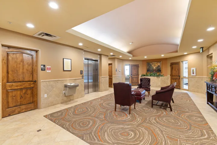 Community lobby with recessed lighting, a wainscoted wall, lofted ceiling, and tile walls