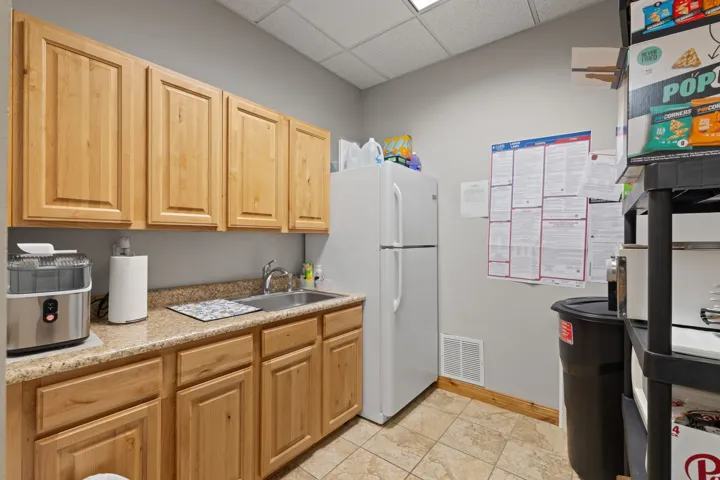 Kitchen with a drop ceiling, light countertops, freestanding refrigerator, and light brown cabinetry