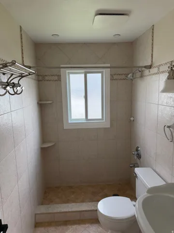 Tiled shower area featuring a window, recessed lighting, and a built-in shower shelf