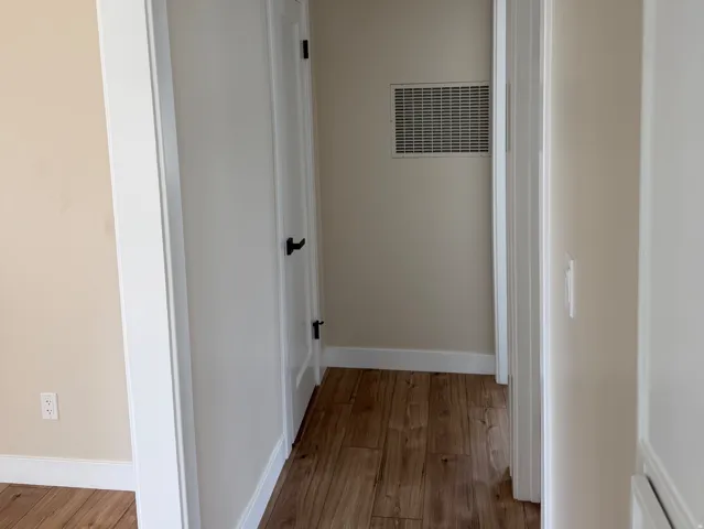 Hallway featuring wood-finish flooring and neutral wall tones