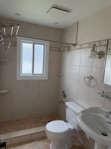Full bathroom featuring a tiled shower enclosure, a white pedestal sink, and a white toilet