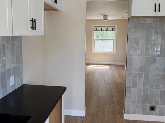 Kitchen featuring white shaker cabinetry with matte black hardware, dark countertops, and a gray subway tile backsplash
