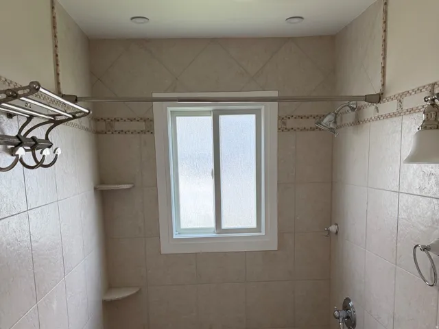 Tiled shower area featuring a window, recessed lighting, and a built-in shower shelf