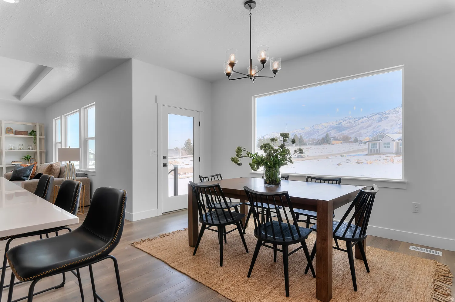 Dining area with light wood-style flooring, suspended lighting, a mountain view, and a textured ceiling