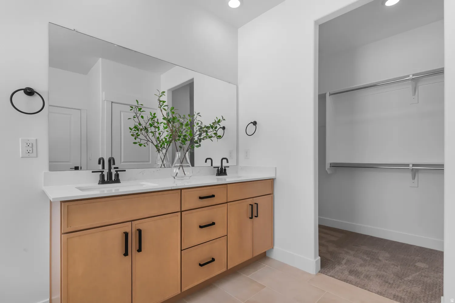 Bathroom featuring double vanity, light tile patterned flooring, a spacious closet, light colored carpet, and recessed lighting