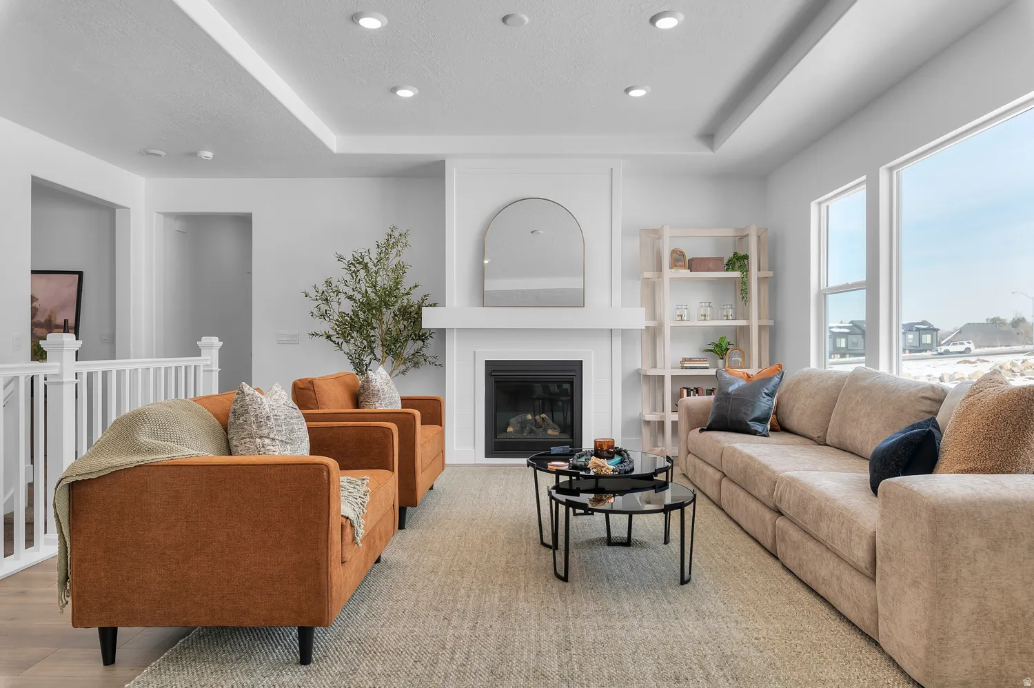 Living room featuring a tray ceiling, a glass covered fireplace, and recessed lighting