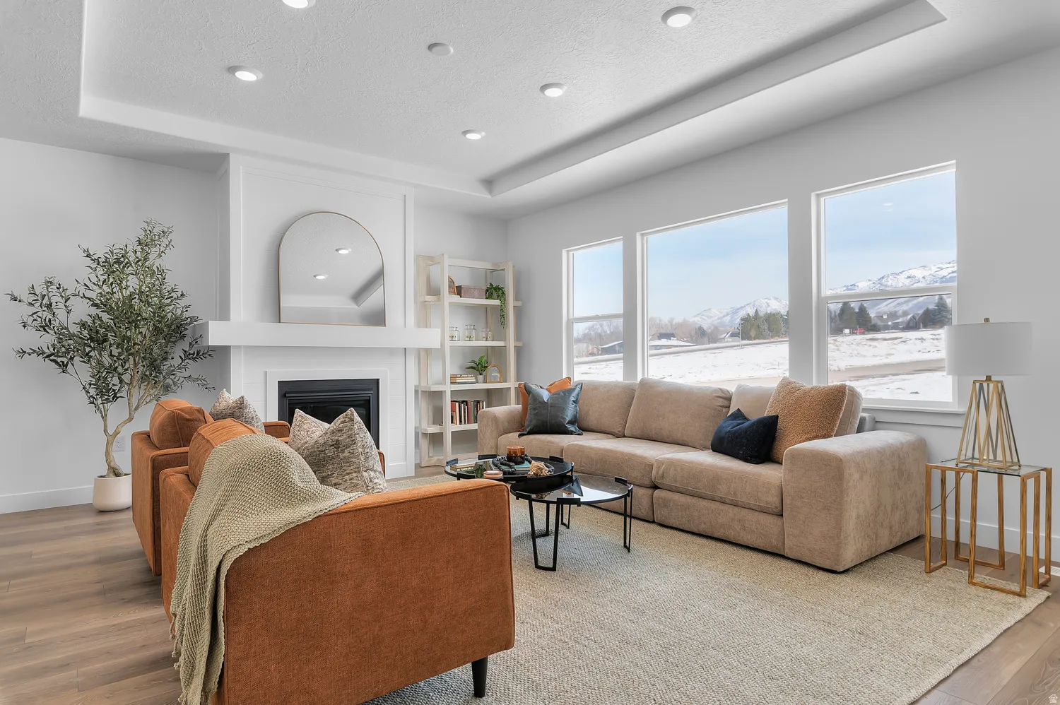 Living room with wood finished floors, a tray ceiling, a mountain view, a fireplace, and a textured ceiling