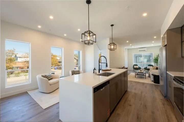 Kitchen featuring open floor plan, appliances with stainless steel finishes, dark wood-style floors, decorative light fixtures, and recessed lighting