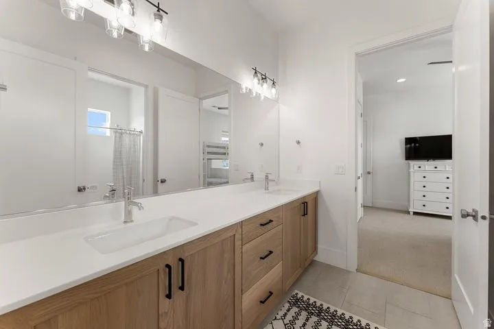 Full bathroom with double vanity, curtained shower, light carpet, and light tile patterned flooring