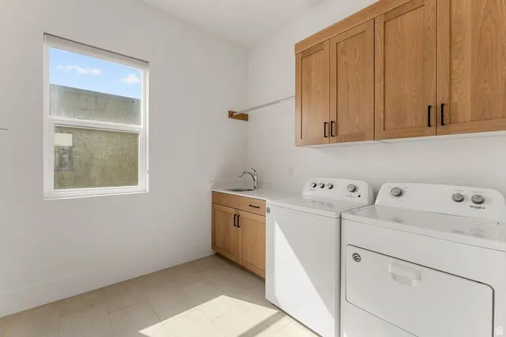 Laundry area with cabinet space, washer and dryer, and light tile patterned flooring