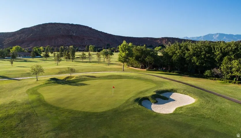 View of home's community featuring view of golf course, a mountain view, and a yard